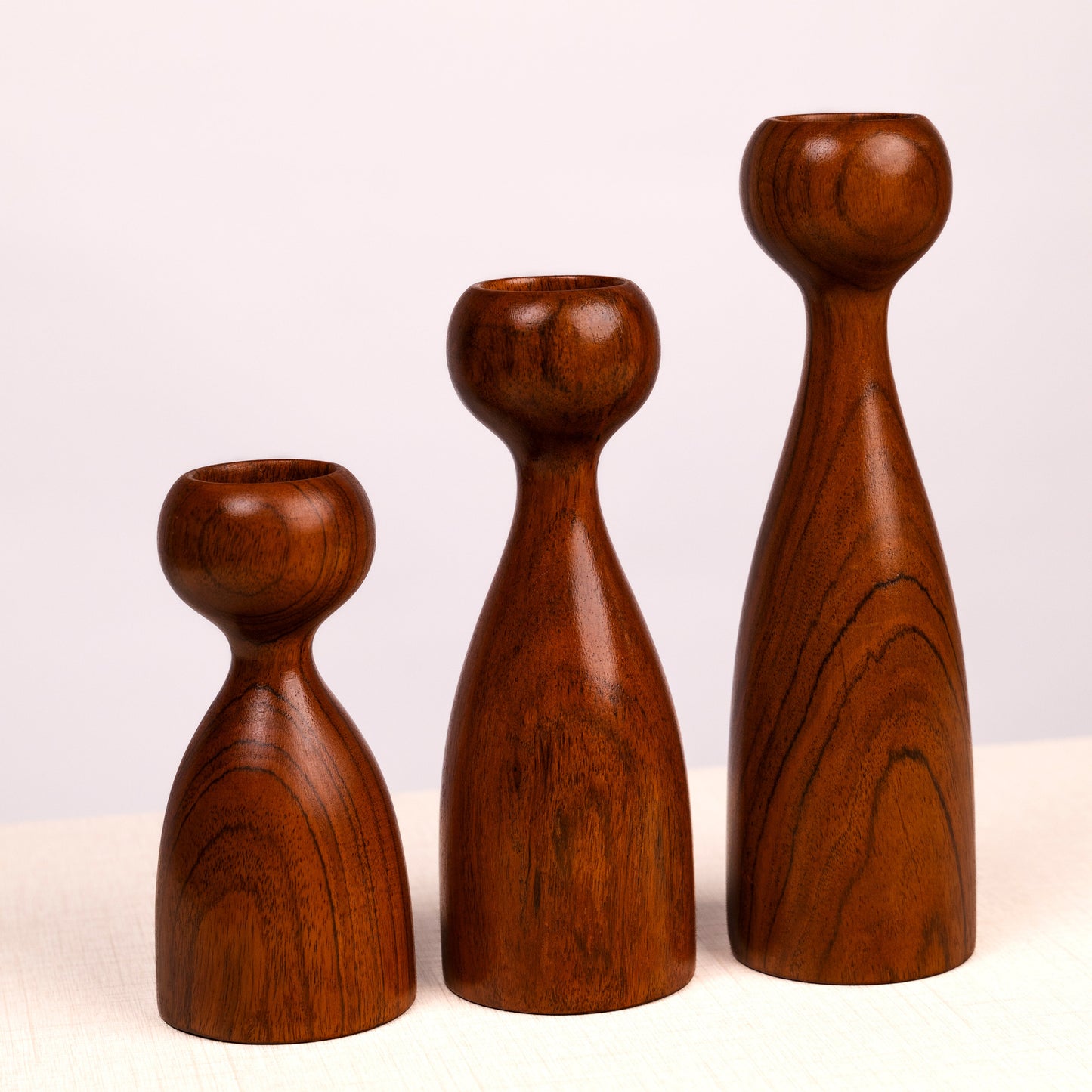 Three wooden candle holders of different sizes on a white background