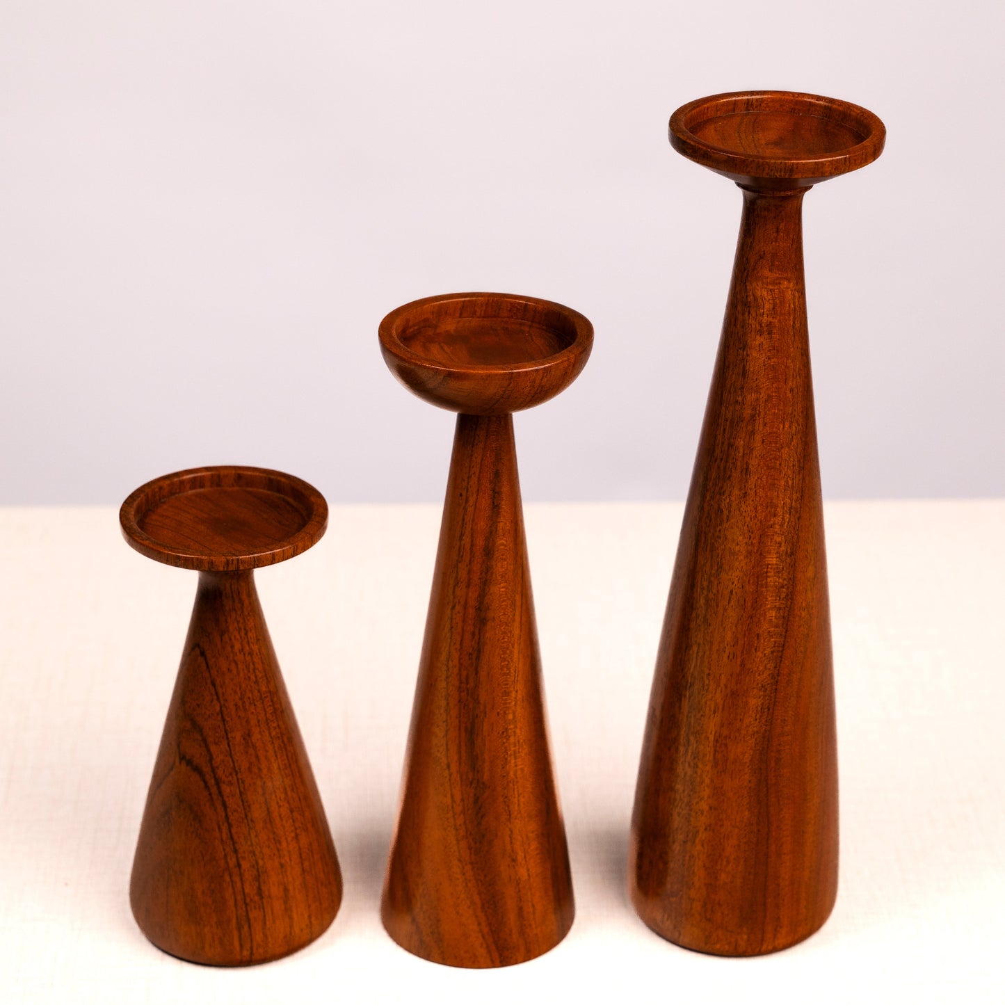 Three wooden candle holders of different heights on a white background