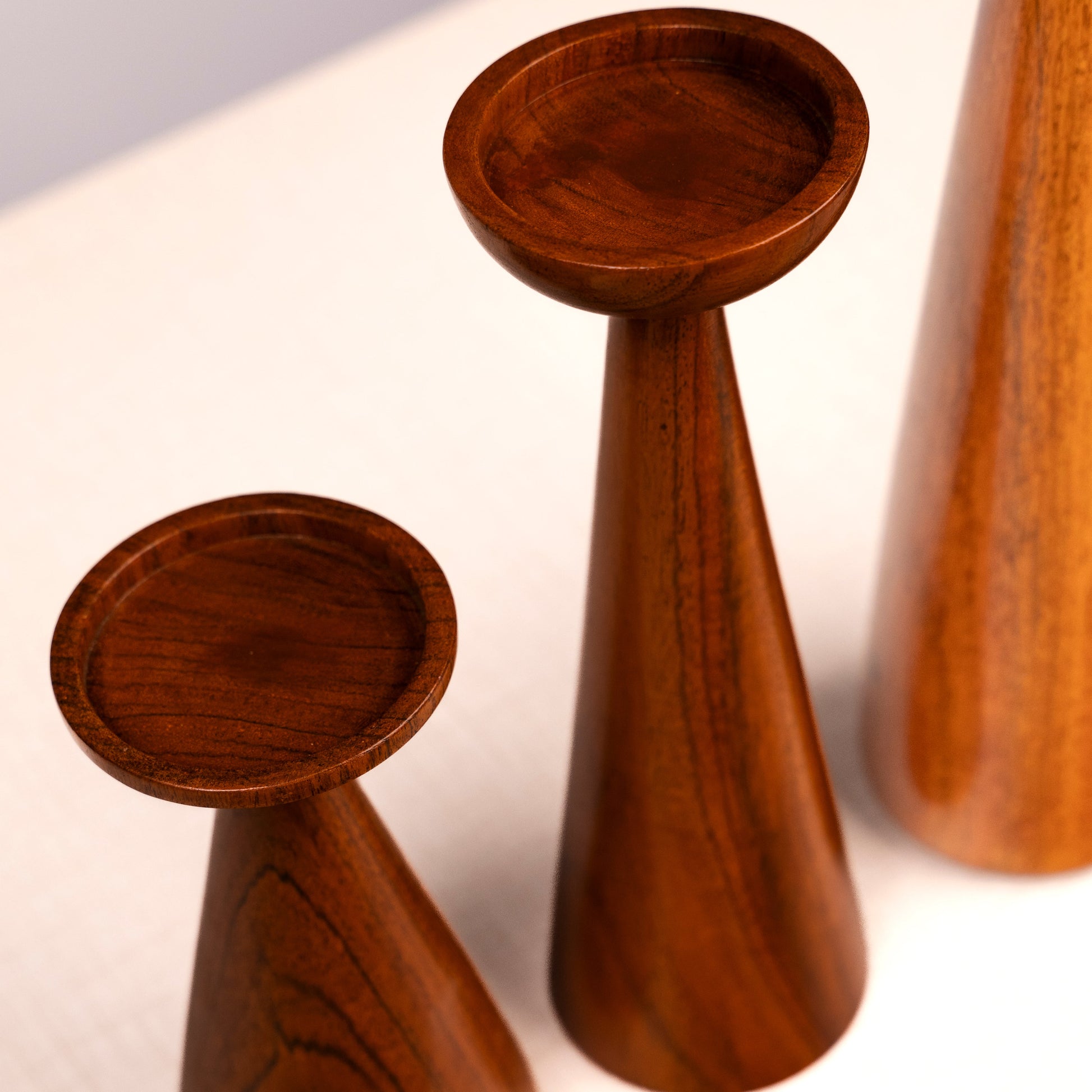 Three wooden candle holders of different sizes on a white background