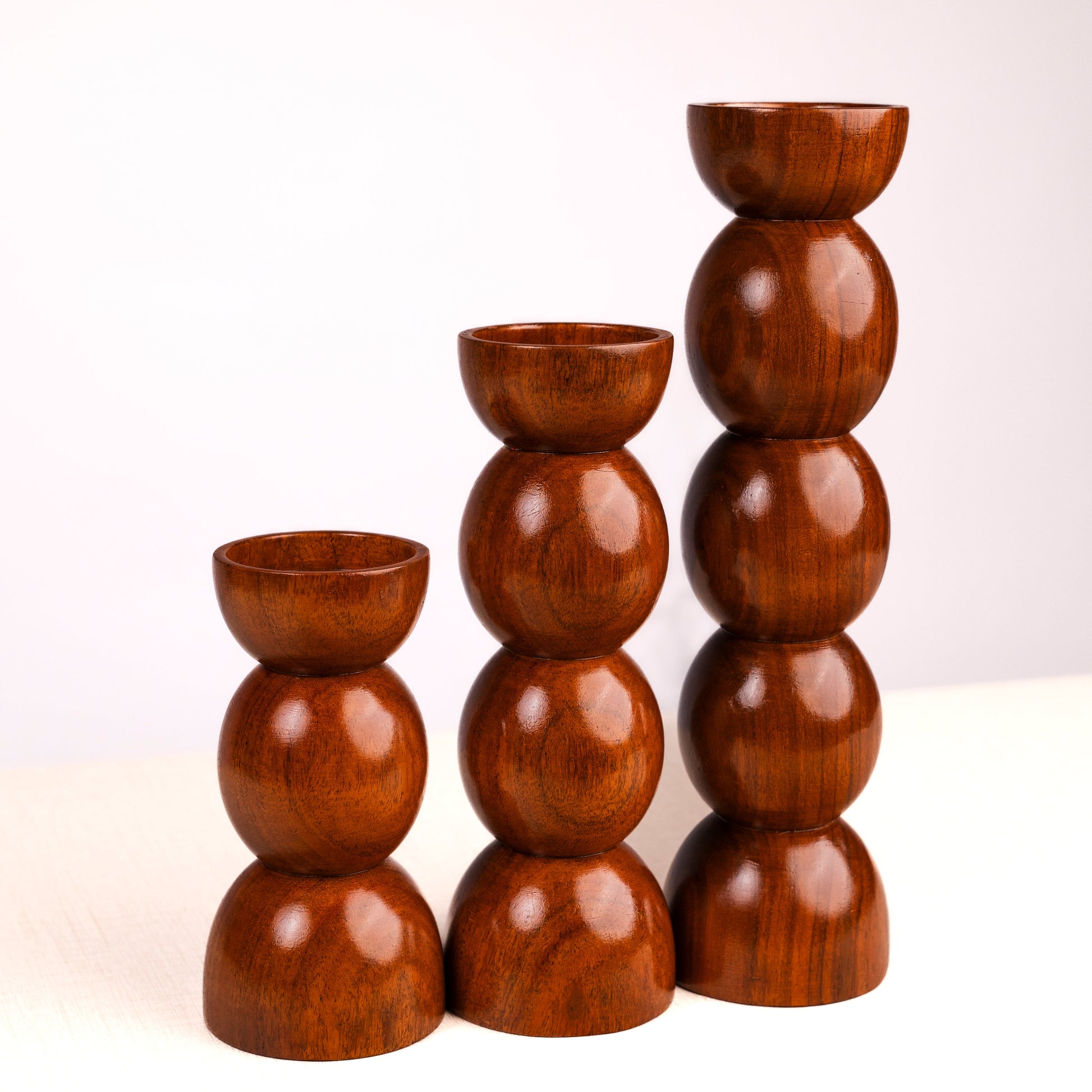 Set of three wooden candle holders stacked on a white background